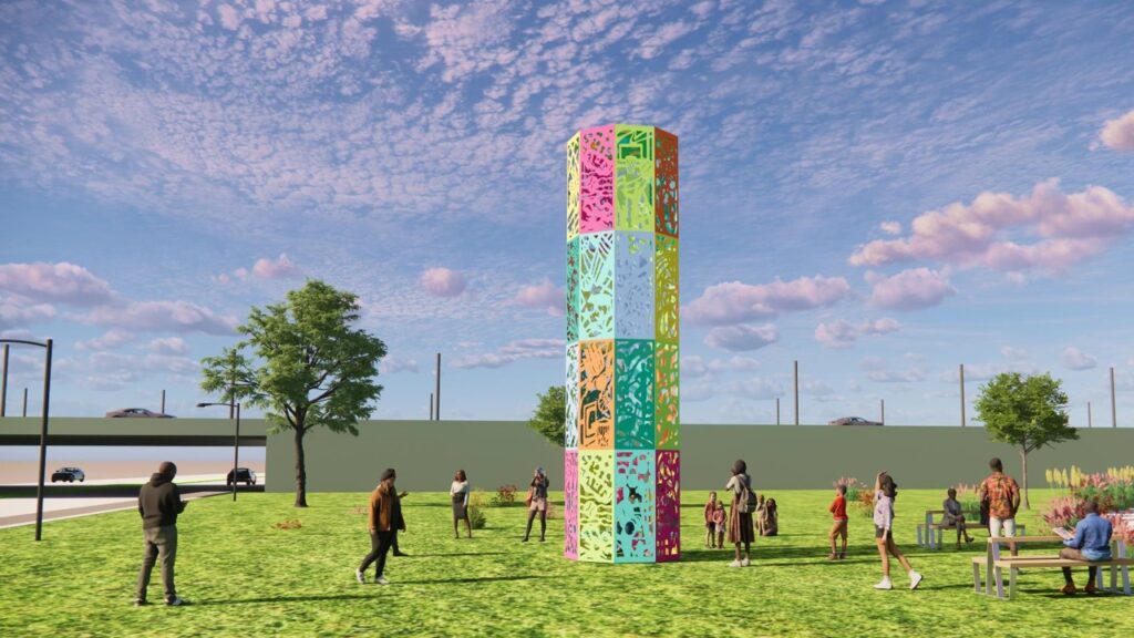 A rendering of 'Life Tower,' a tall rectangular column sculpture installed in a grassy park setting during the day. The tower is made up of a grid of colorful square panels in pink, teal, orange, yellow, and maroon, each featuring intricate cutout patterns of organic and figurative forms. Figures of visitors gather around the base, with trees, benches, and a highway sound wall visible in the background under a partly cloudy sky.
